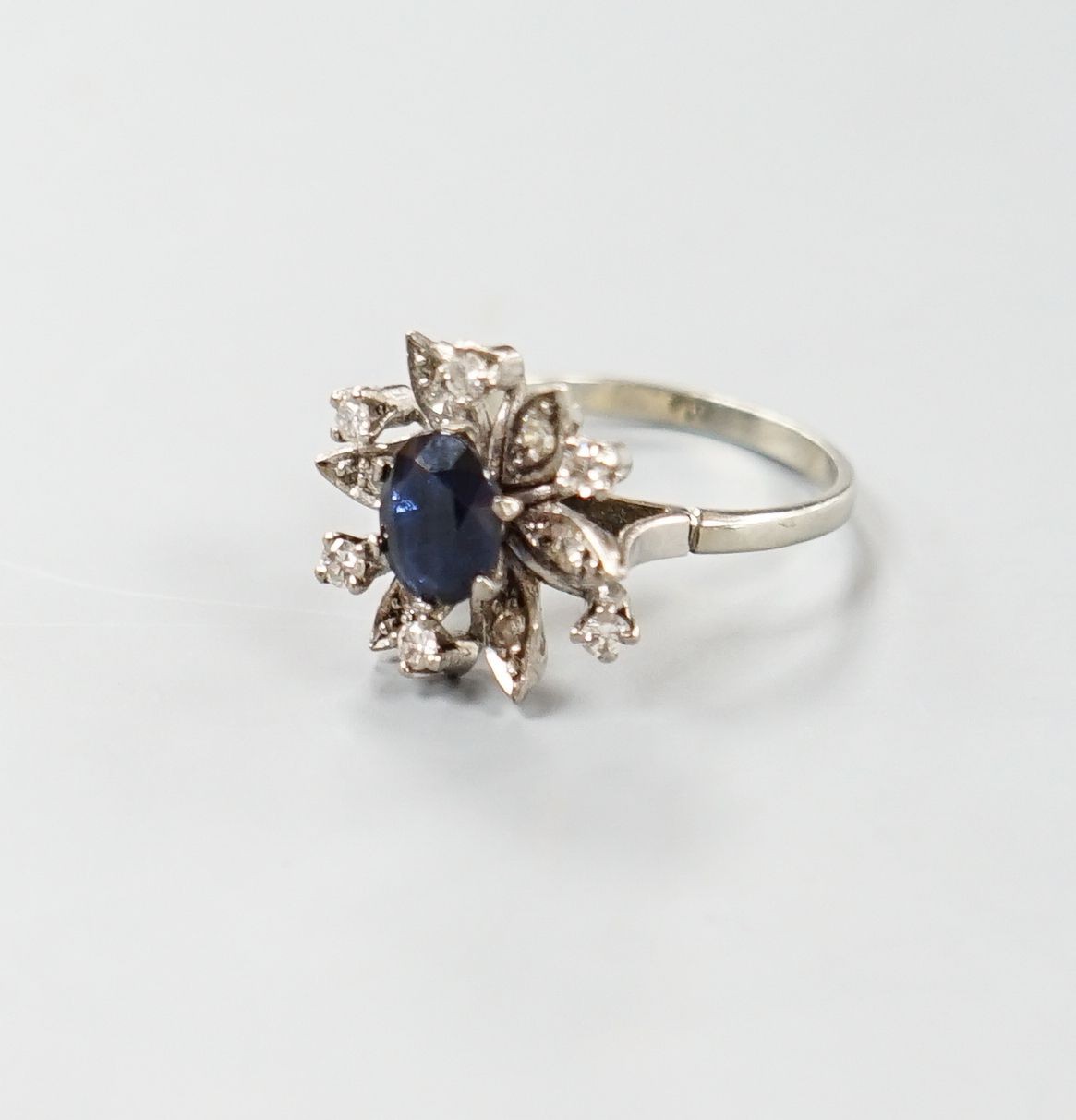A 1930's 18ct white gold, sapphire and diamond cluster set flower head ring, size Q/R